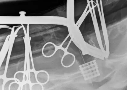 A black and white photo of scissors hanging from a rack.